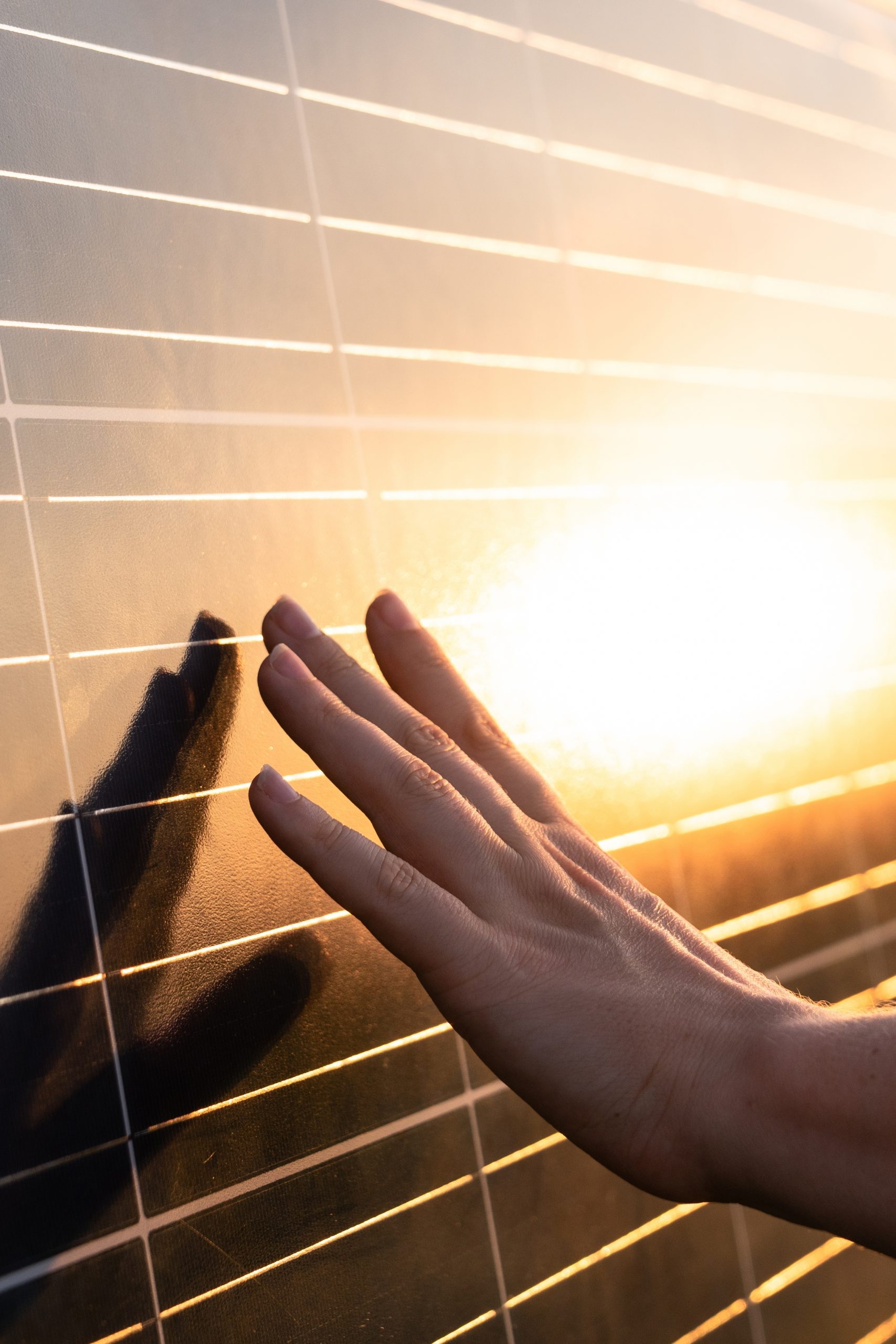 close up,of,a,hand,touching,a,solar,panel,at,sunset.